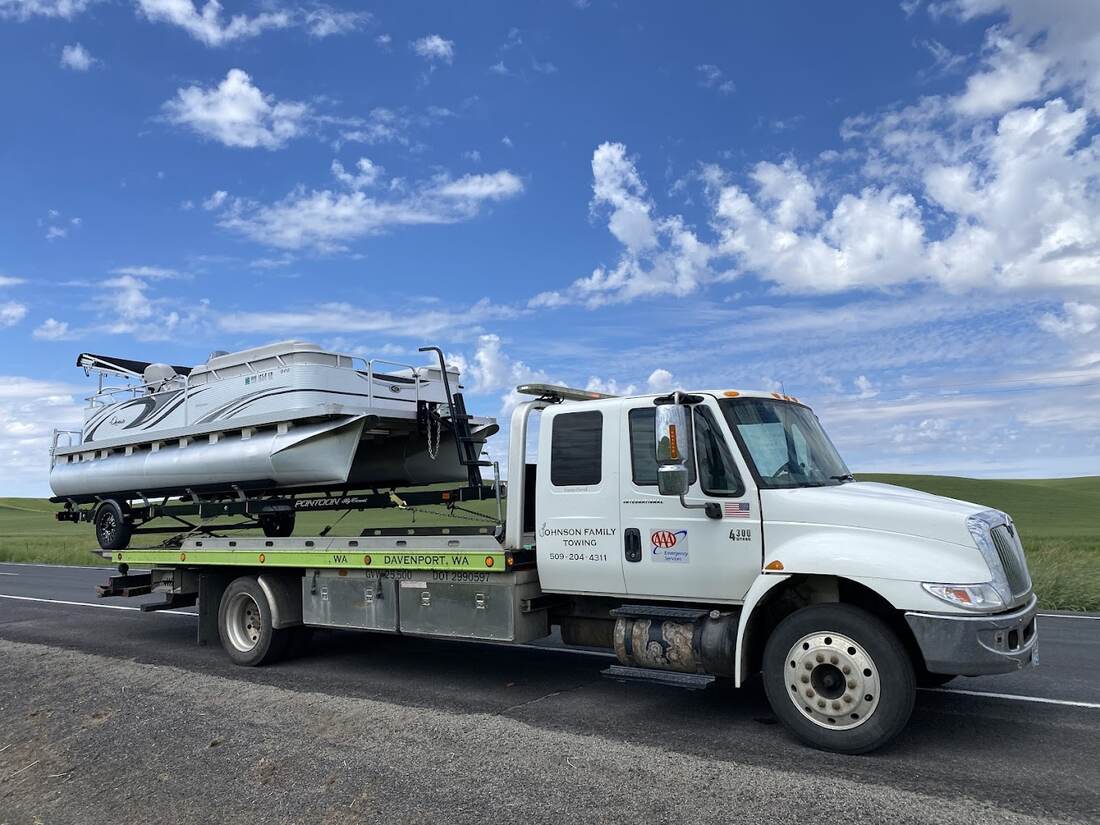 Johnson Family Towing rollback hauling a pontoon boat